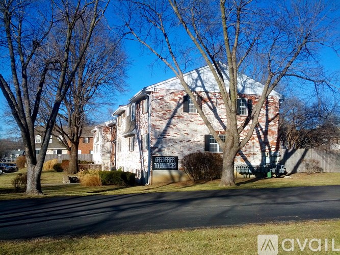 A large red brick house with a tree in front.