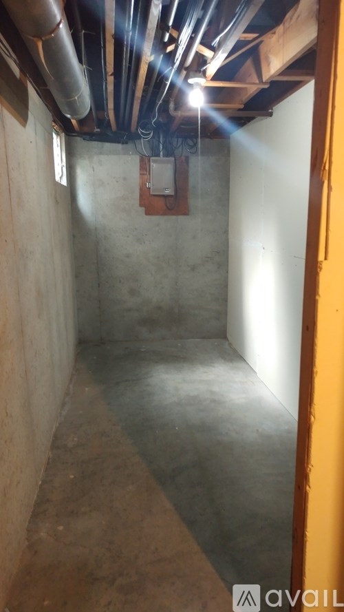 A room with a concrete floor and walls, with a yellow door on the right side.