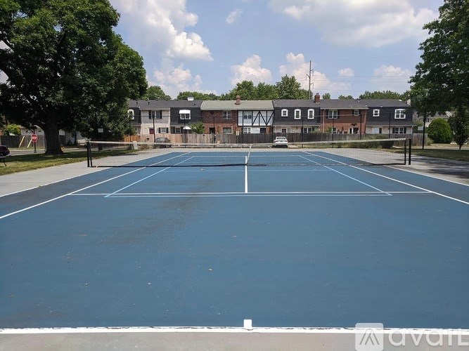 A tennis court is surrounded by a fence and a building.