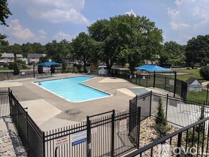 A pool surrounded by a black fence with a sign that says "Apartments".