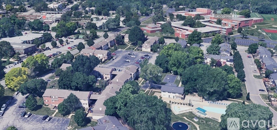 An aerial view of a school with a swimming pool and trees.