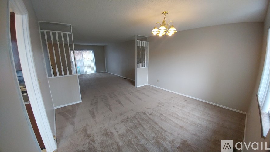 A room with a chandelier and a window with blinds.