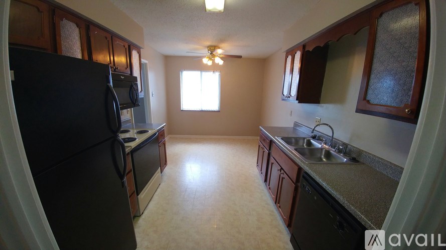 A kitchen with a black refrigerator and brown cabinets.