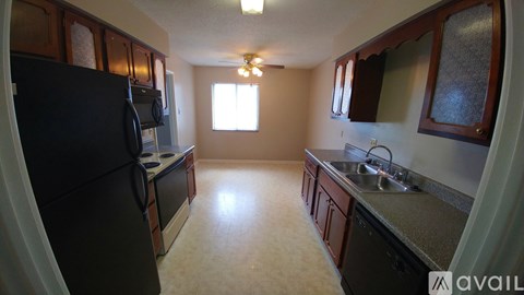 A kitchen with a black refrigerator and brown cabinets.