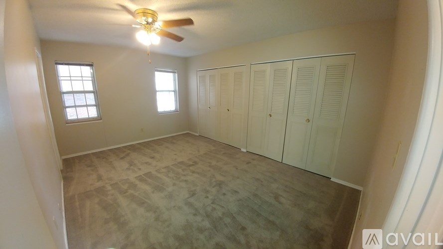 A room with a ceiling fan and two windows.