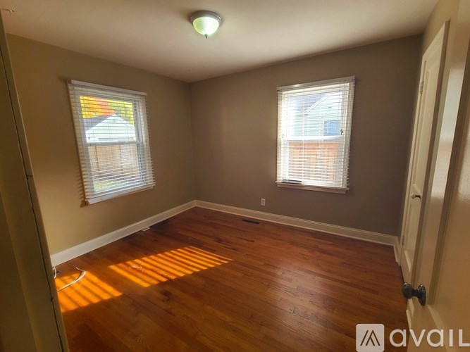 A room with wooden floors and two windows.