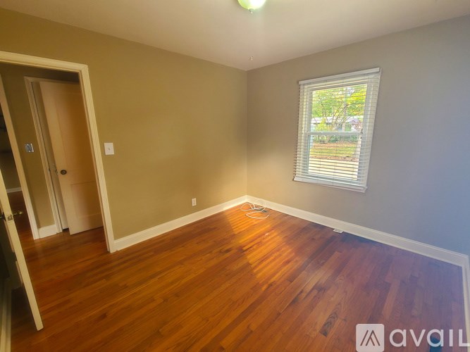 A room with wooden flooring and a window with blinds.