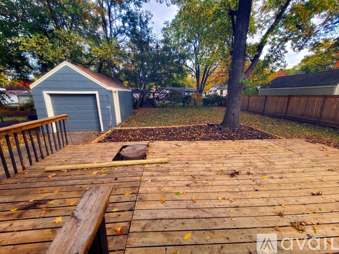 A wooden deck with a bench and a tree in the backyard.