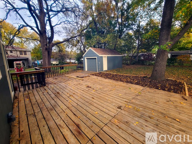 A wooden deck with a table and chairs in the foreground and a shed in the background.