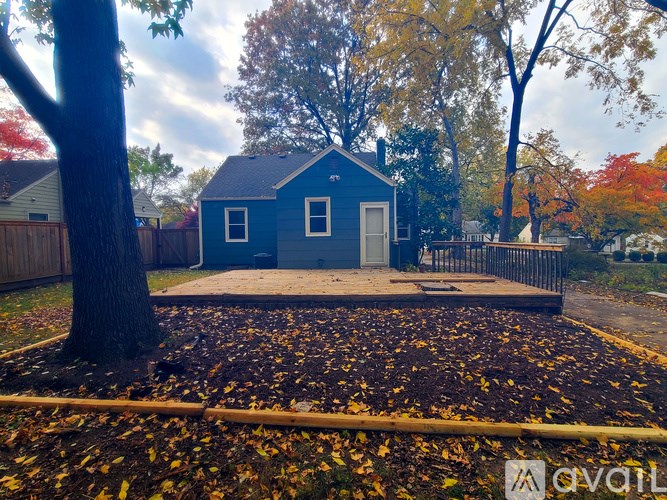 A small blue house with a white door and a brown fence.