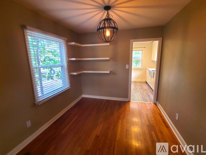 A room with wooden floors and a window with blinds.