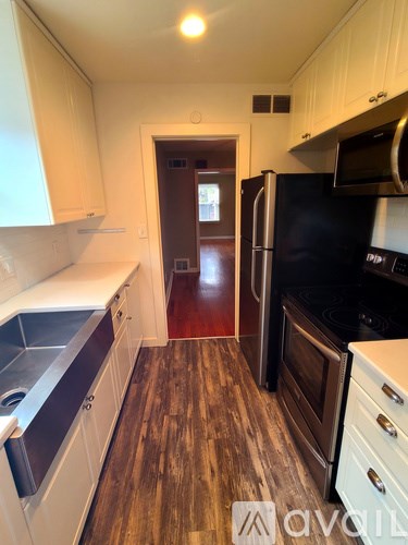 A kitchen with a black fridge and stove top oven.