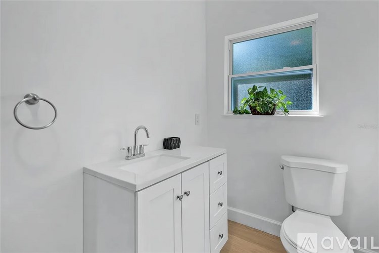 A bathroom with a toilet, sink, and a window.