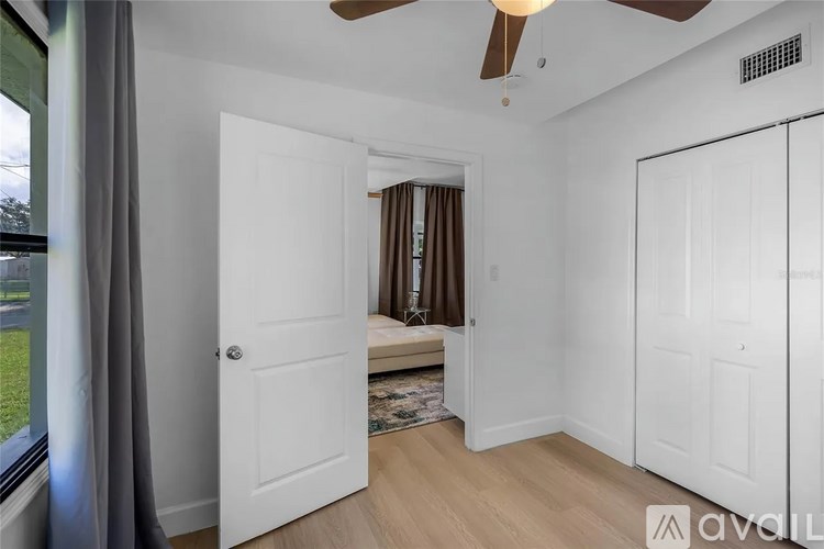 A room with a ceiling fan and a bed with brown curtains.