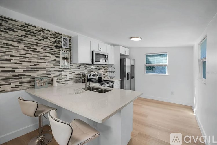 A modern kitchen with a stone backsplash and a bar area.