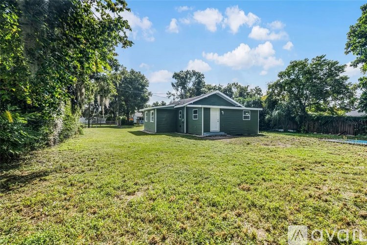 A small house is surrounded by greenery and trees.
