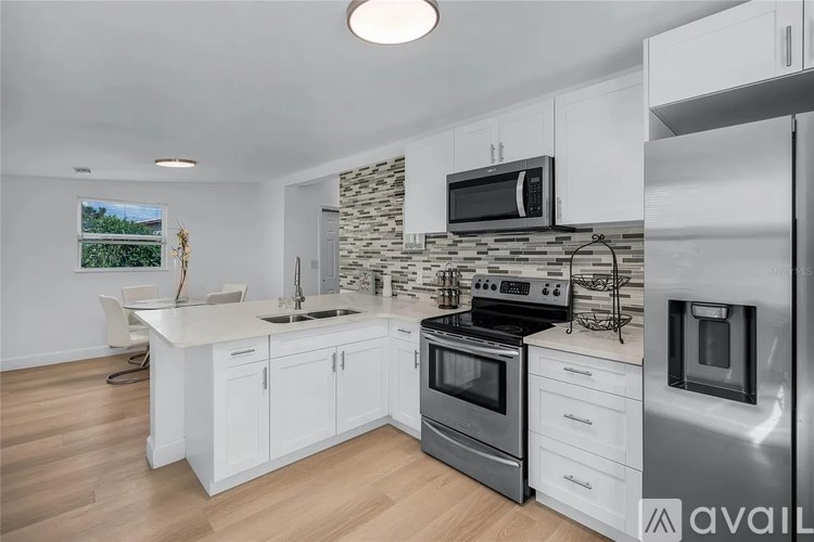 A modern kitchen with white cabinets and stainless steel appliances.