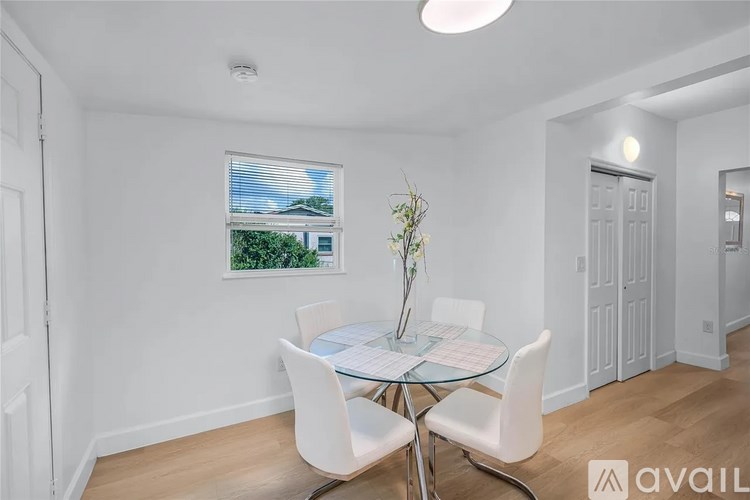 A dining room with a glass table and white chairs.
