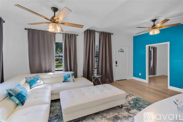 A living room with a white couch and a ceiling fan.