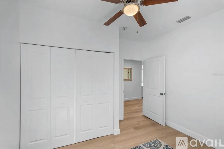 A room with a ceiling fan and a rug on the floor.