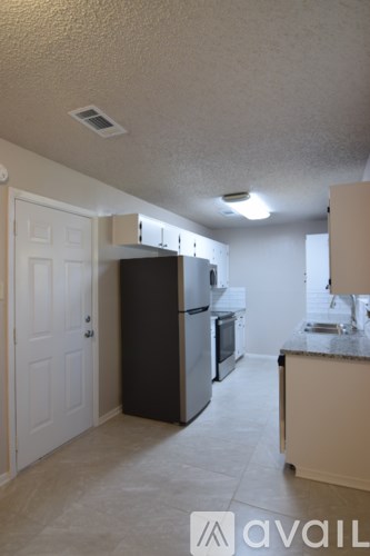 A kitchen with a refrigerator, sink, and cabinets.