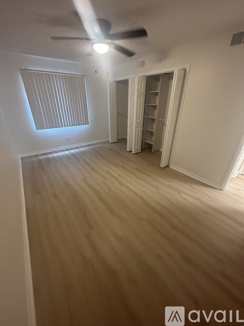 A room with a ceiling fan and a window with blinds.