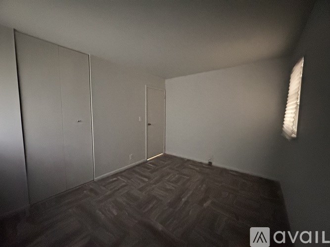 A room with a carpeted floor and a wall with a window.