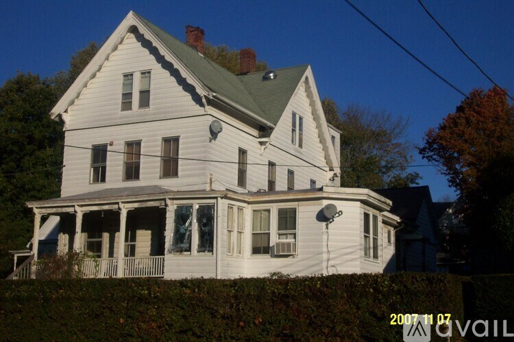 A large white house with a green roof and a balcony.