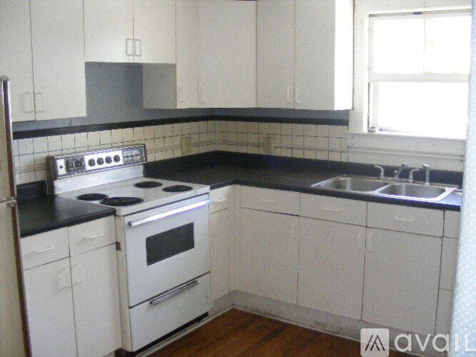 A kitchen with white cabinets and a black countertop.