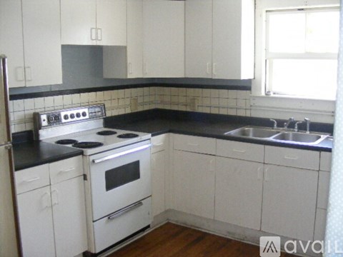 A kitchen with white cabinets and a black countertop.