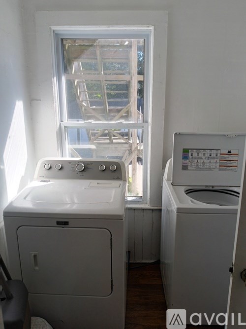 A white washing machine and dryer in a small room with a window.