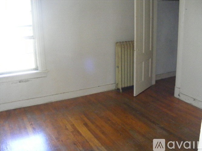 A room with wooden floors and a window with blinds.