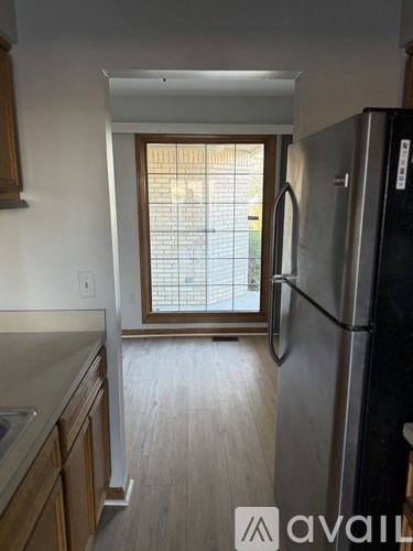 A kitchen with a black fridge and wooden cabinets.