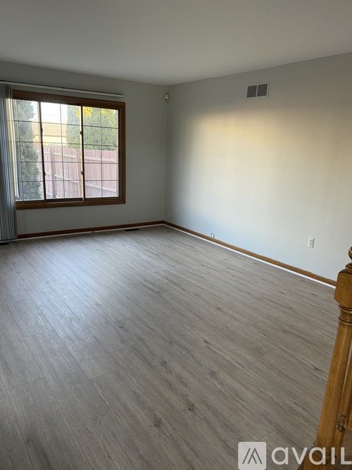 A room with wooden flooring and a window with blinds.