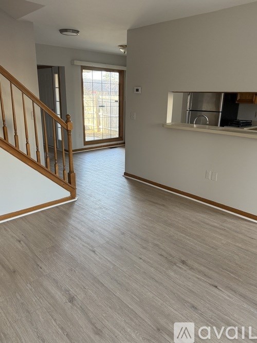 A spacious room with wooden flooring and a staircase leading to another level.