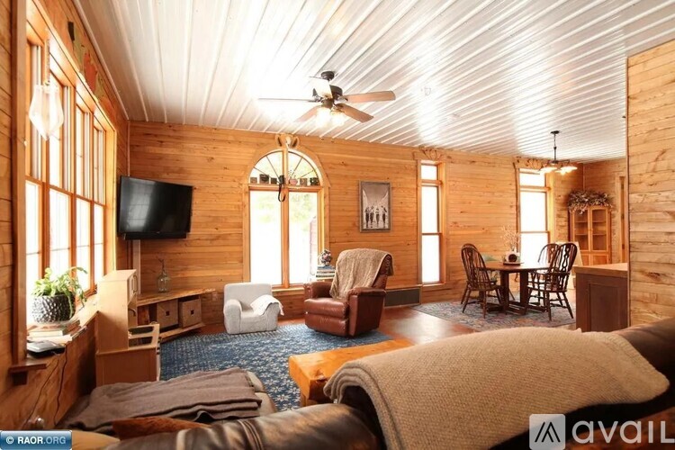 A cozy living room with wooden walls and a ceiling fan.