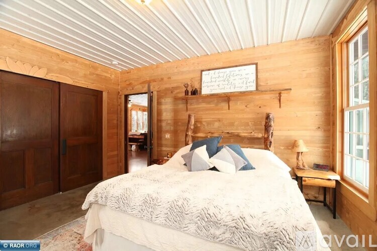 A bedroom with a bed, wooden walls, and a window.
