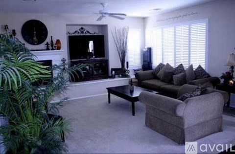 A living room with a grey couch, a black coffee table, and a fireplace with a mirror above it.