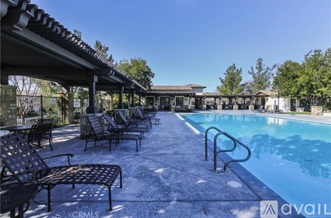 A pool area with a row of lounge chairs and a pool.
