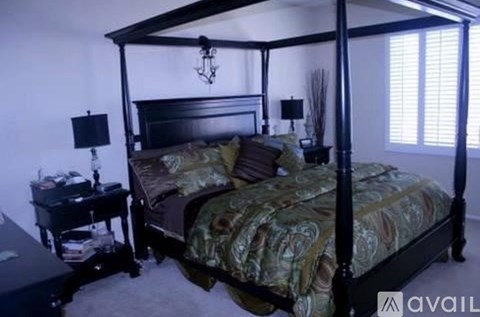 A bedroom with a four poster bed and a desk.