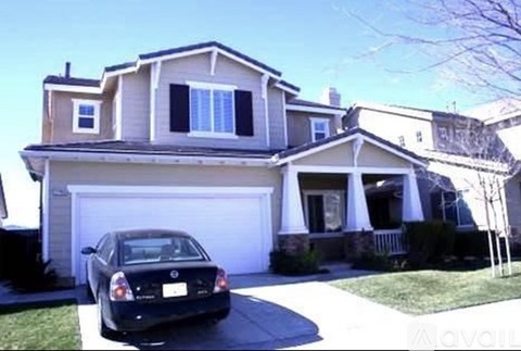 A black car is parked in front of a two-story house.
