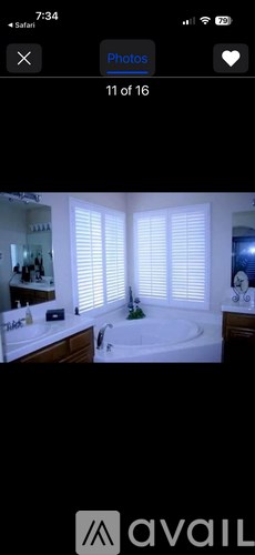 A bathroom with a large tub and a window with blinds.