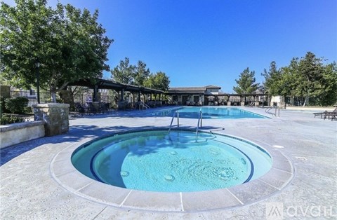 A round swimming pool with a bench and trees around it.