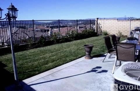 A patio with a table and chairs is surrounded by a black fence.