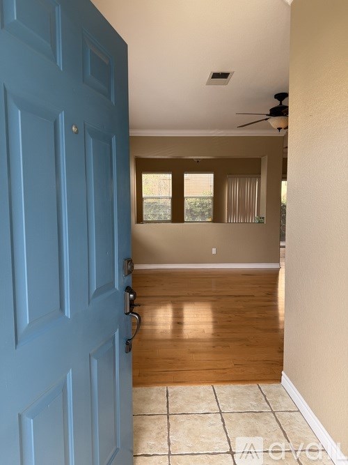 A room with a blue door and a ceiling fan.