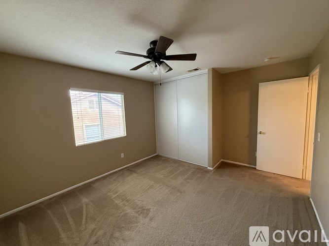 A room with a ceiling fan and a window with blinds.