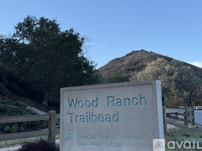 A sign for Wood Ranch Trailhead stands in front of a mountain.