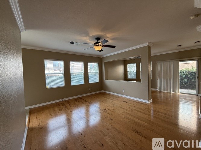 A spacious room with wooden floors and a ceiling fan.