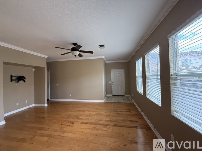 A spacious room with wooden floors and a ceiling fan.