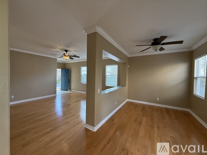 A spacious room with wood flooring and a ceiling fan.
